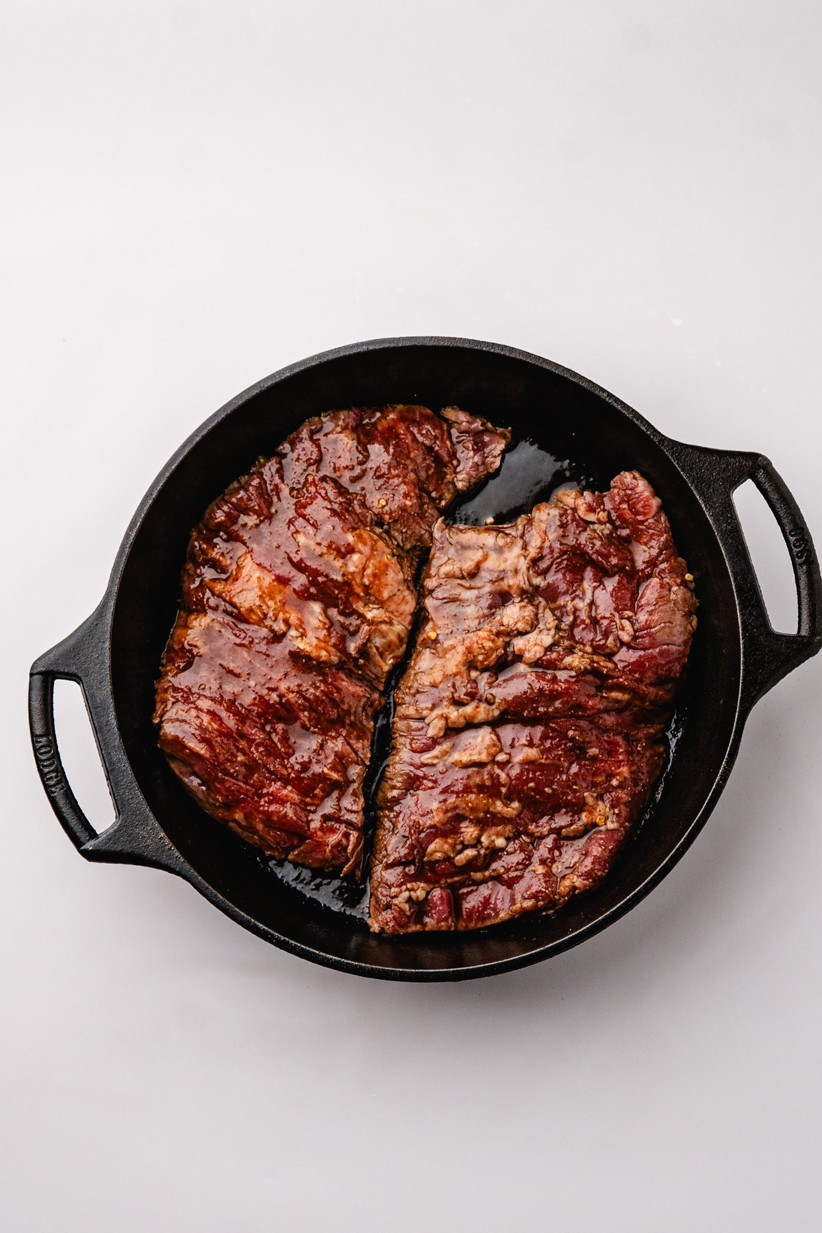 Marinated steak searing in a hot cast iron skillet