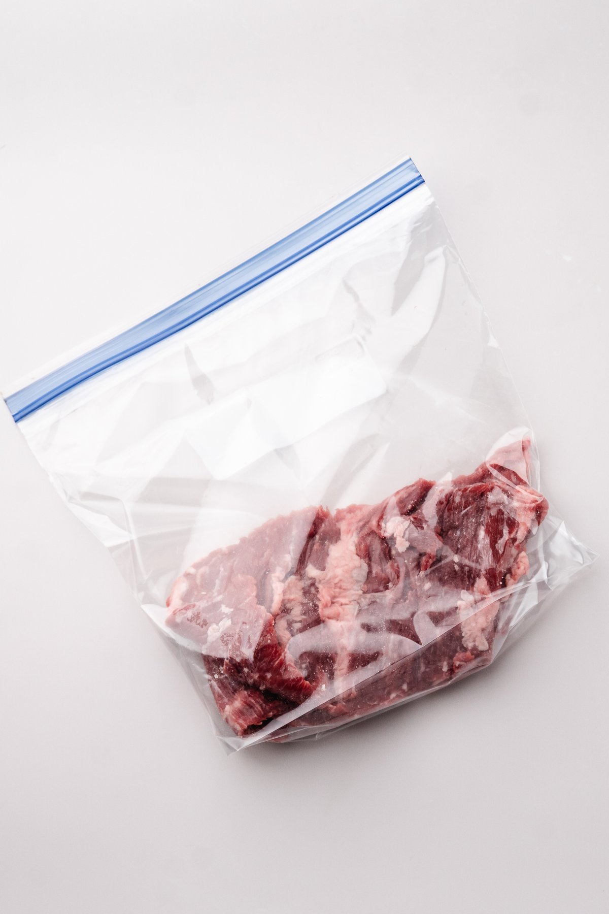 Raw skirt steak in a zip top bag before marinating