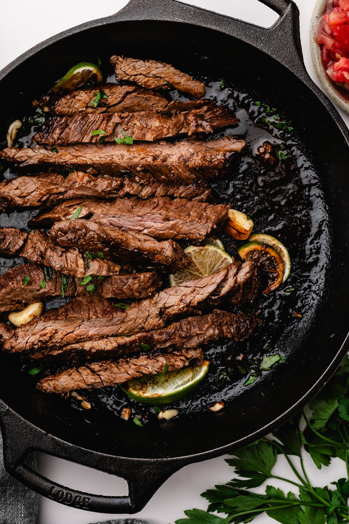 Sliced marinated steak fanned out in a cast iron skillet