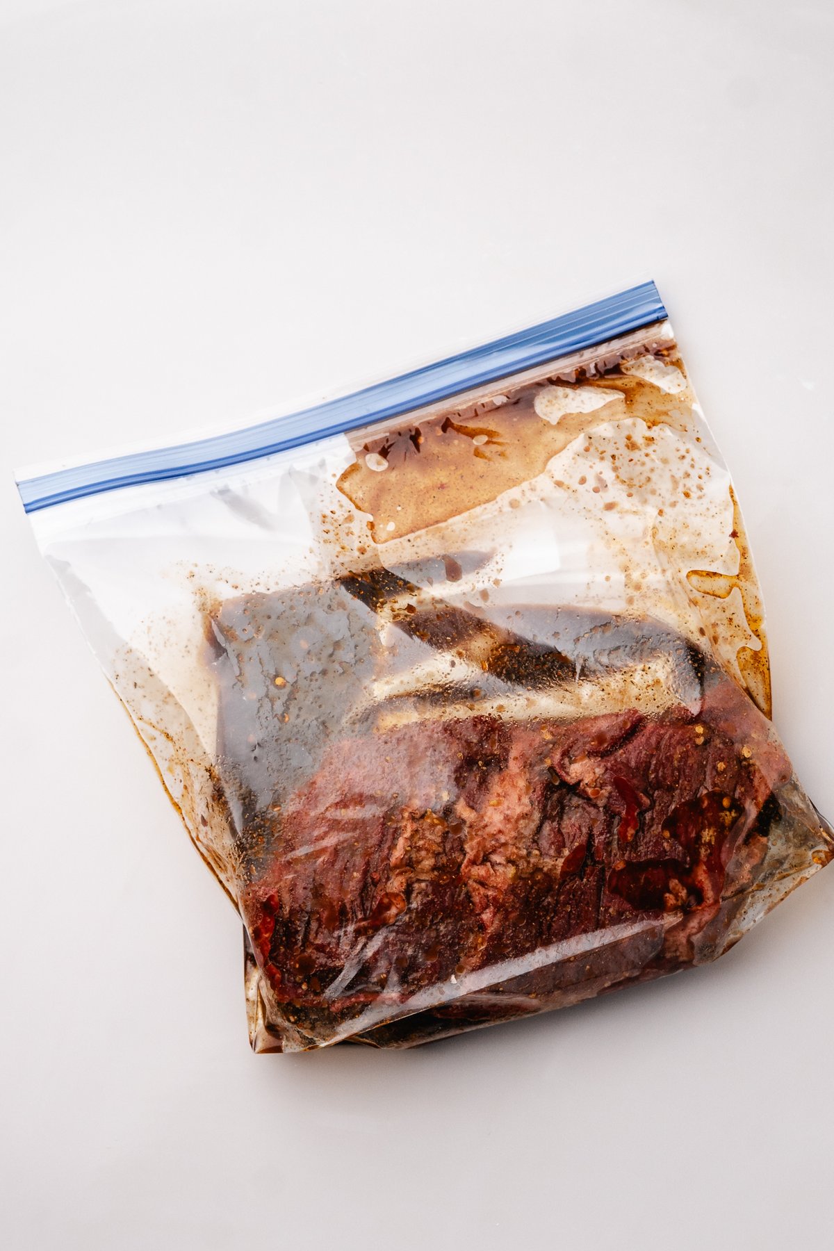 Skirt steak marinating in a zip top bag with steak marinade