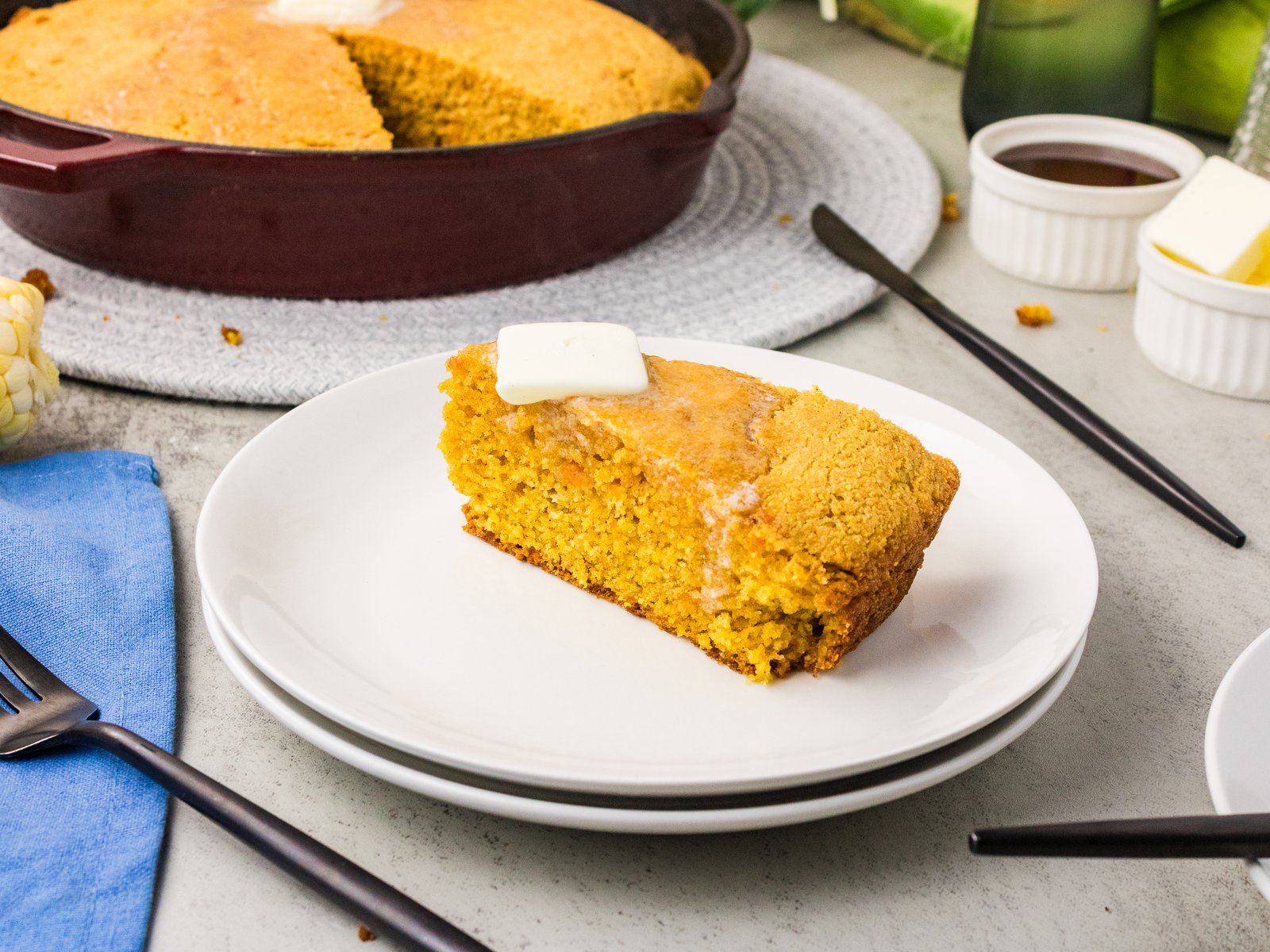 Slice of sweet potato cornbread on a white plate with a pat of butter
