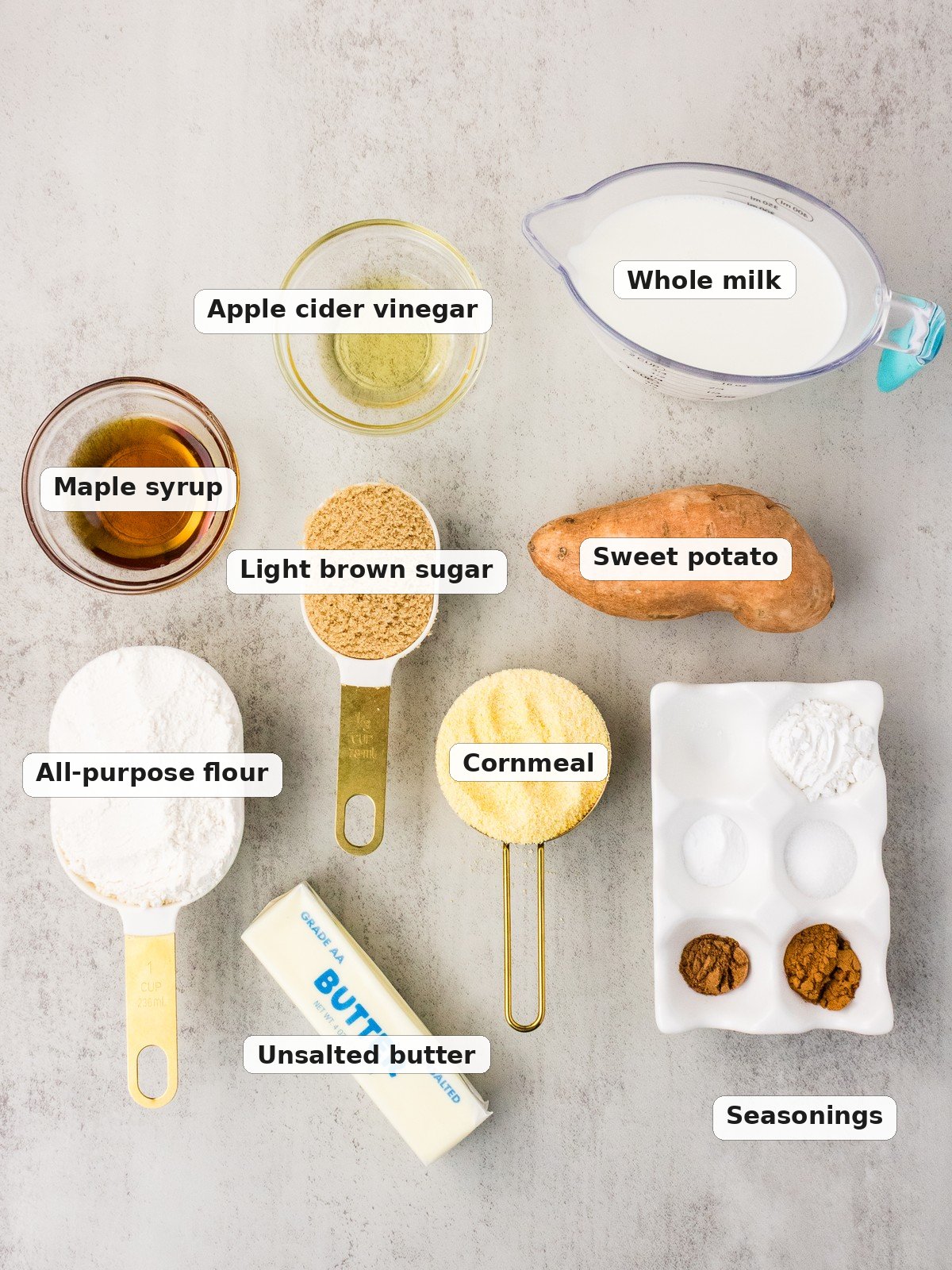 Ingredients for sweet potato cornbread labeled and laid out on a gray surface