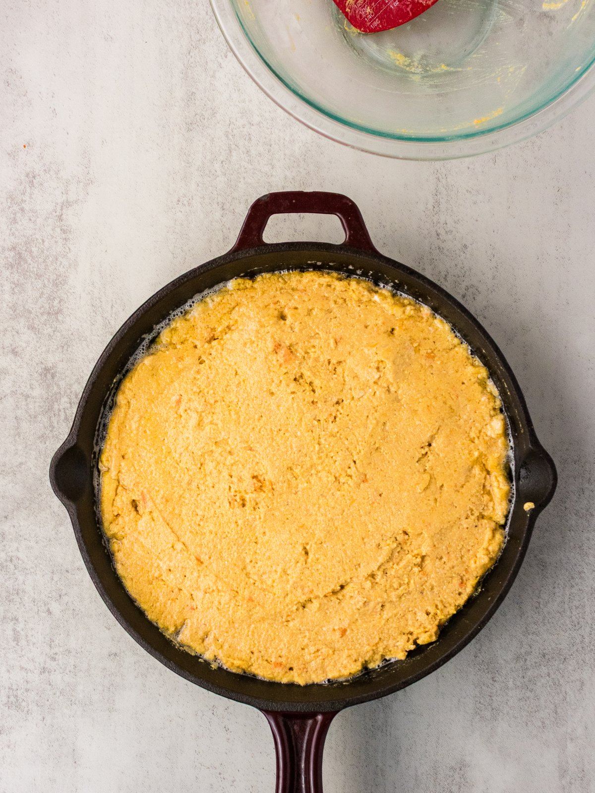 Sweet potato cornbread batter poured into a hot buttered cast iron skillet