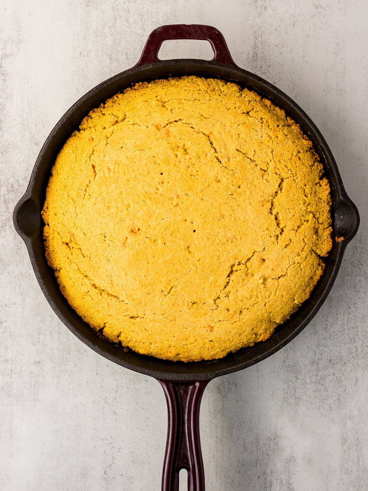 Baked sweet potato cornbread golden and domed in a cast iron skillet