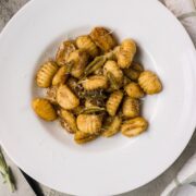 Brown butter sage gnocchi plated on a white dinner plate with crispy sage leaves