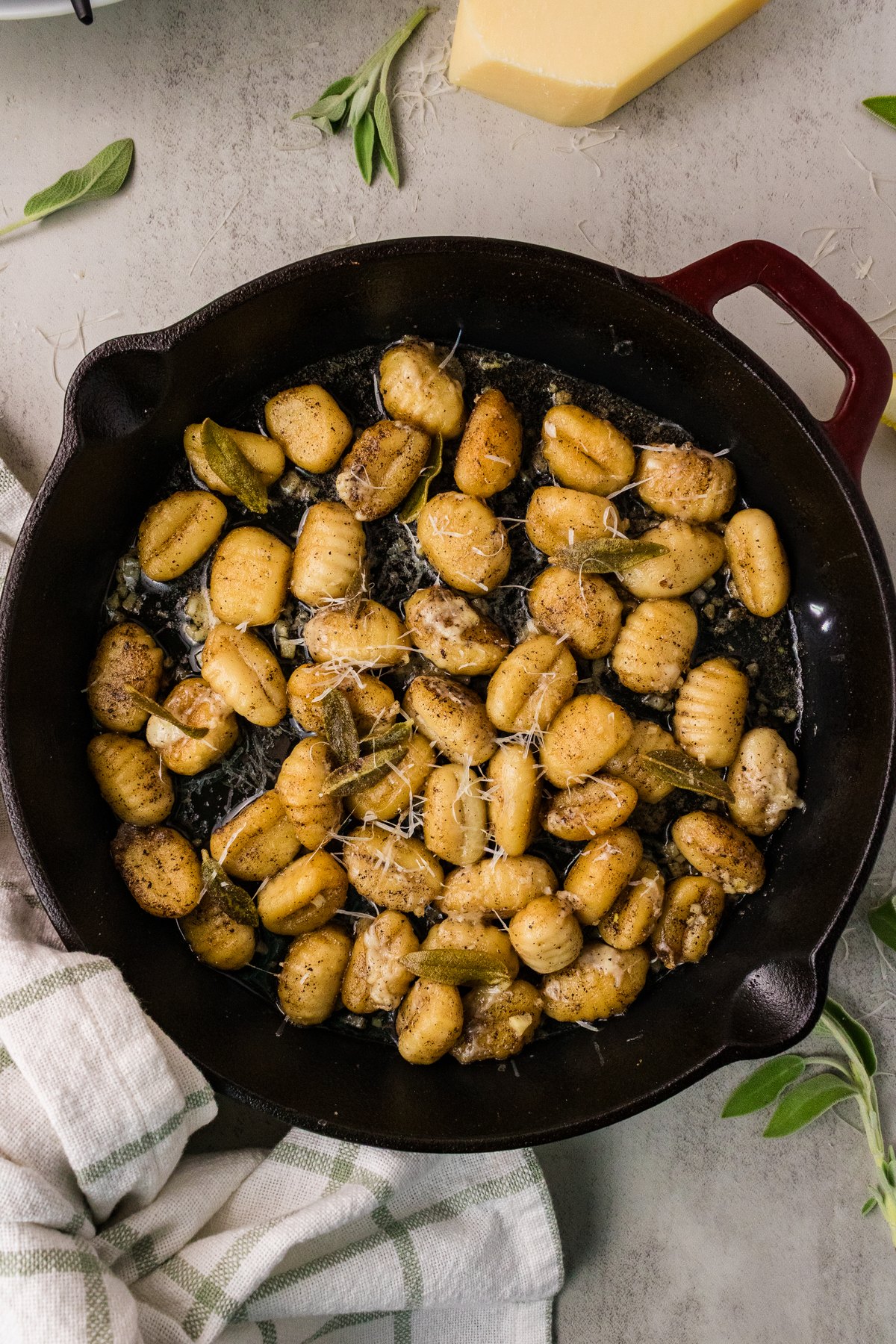 Brown butter sage gnocchi in a cast iron skillet topped with crispy sage and grated Parmesan