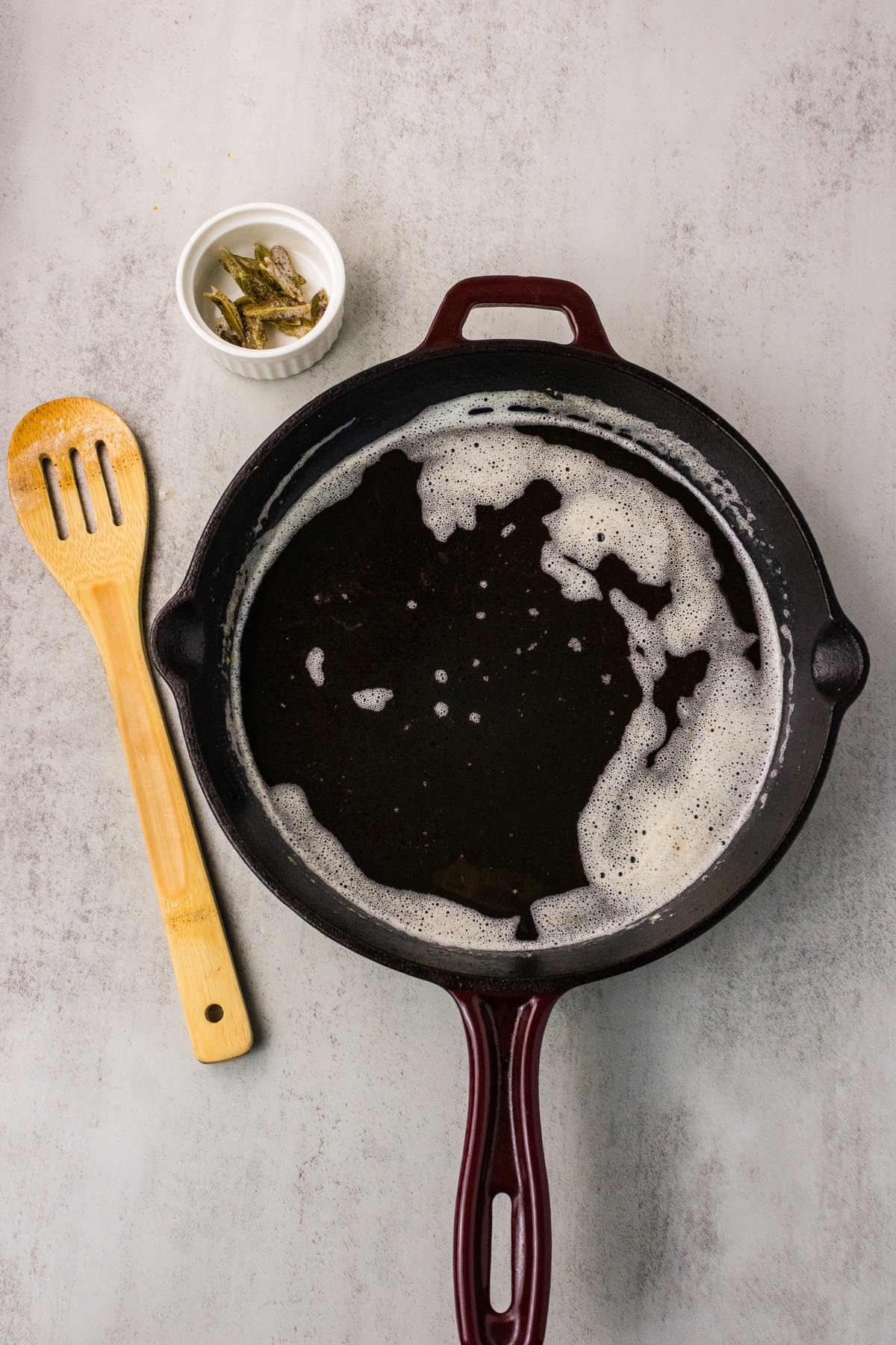 Butter foaming with whole fresh sage leaves in a cast iron skillet