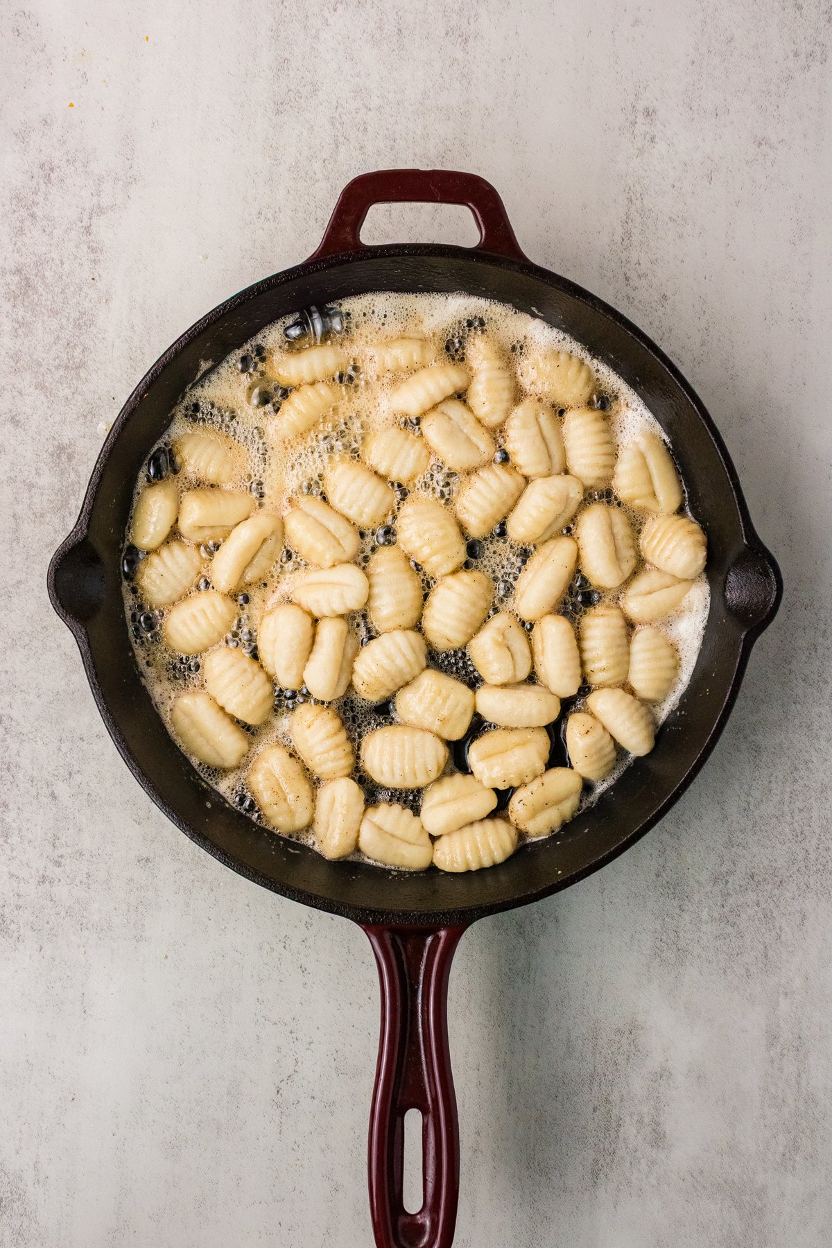 Drained gnocchi arranged in a single layer in a cast iron skillet
