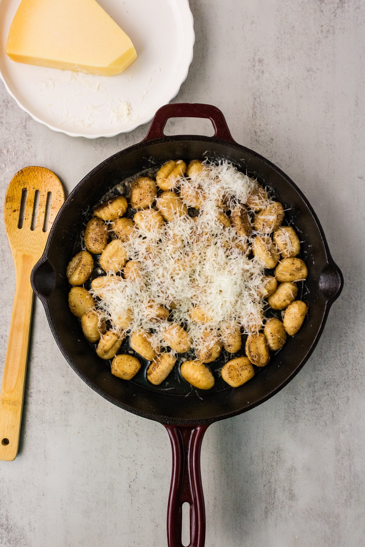 Finely grated Parmesan tossed with crispy gnocchi in a cast iron skillet