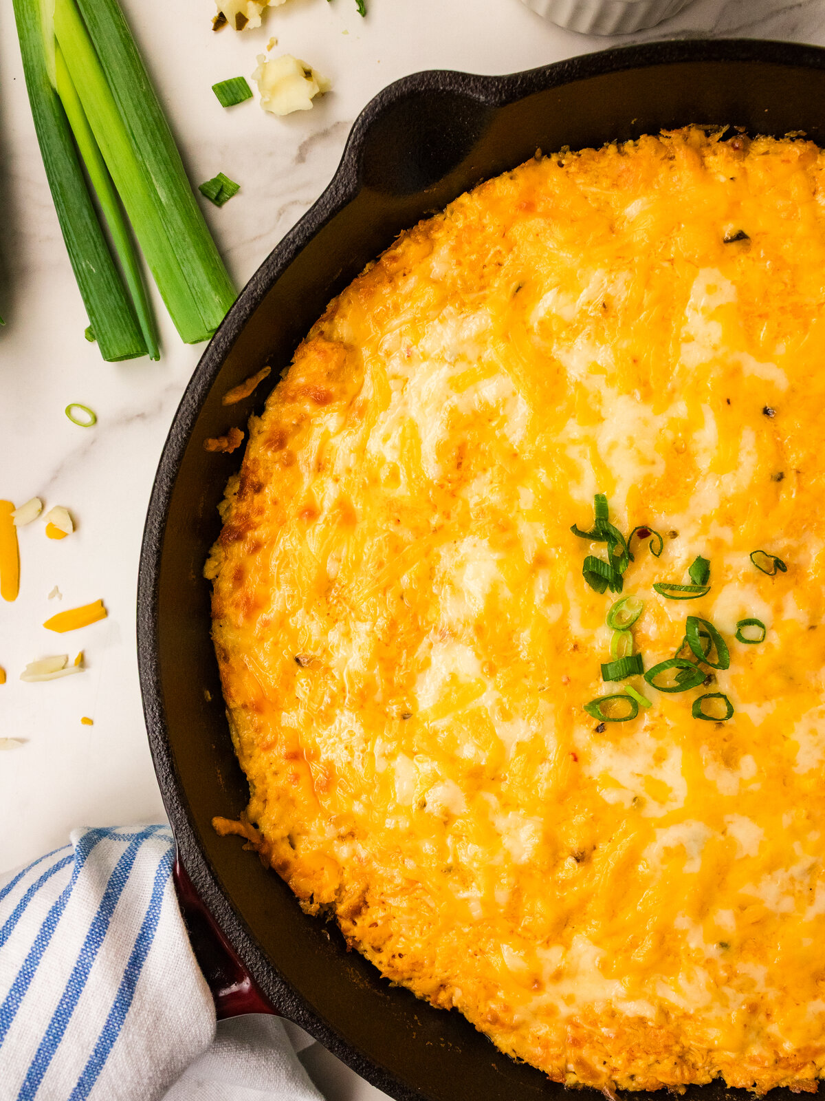 Overhead cast iron skillet of buffalo chicken dip topped with green onions