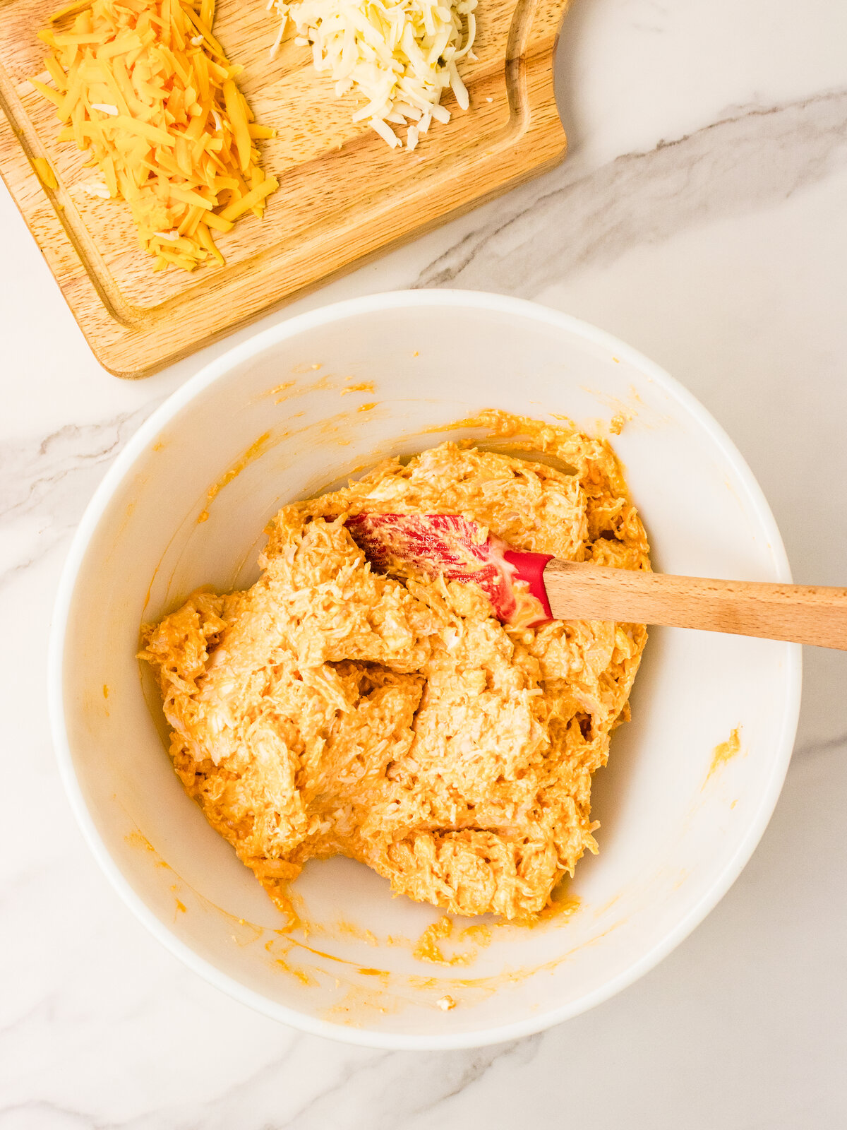 Shredded cheddar and pepper jack stirred into buffalo chicken mixture
