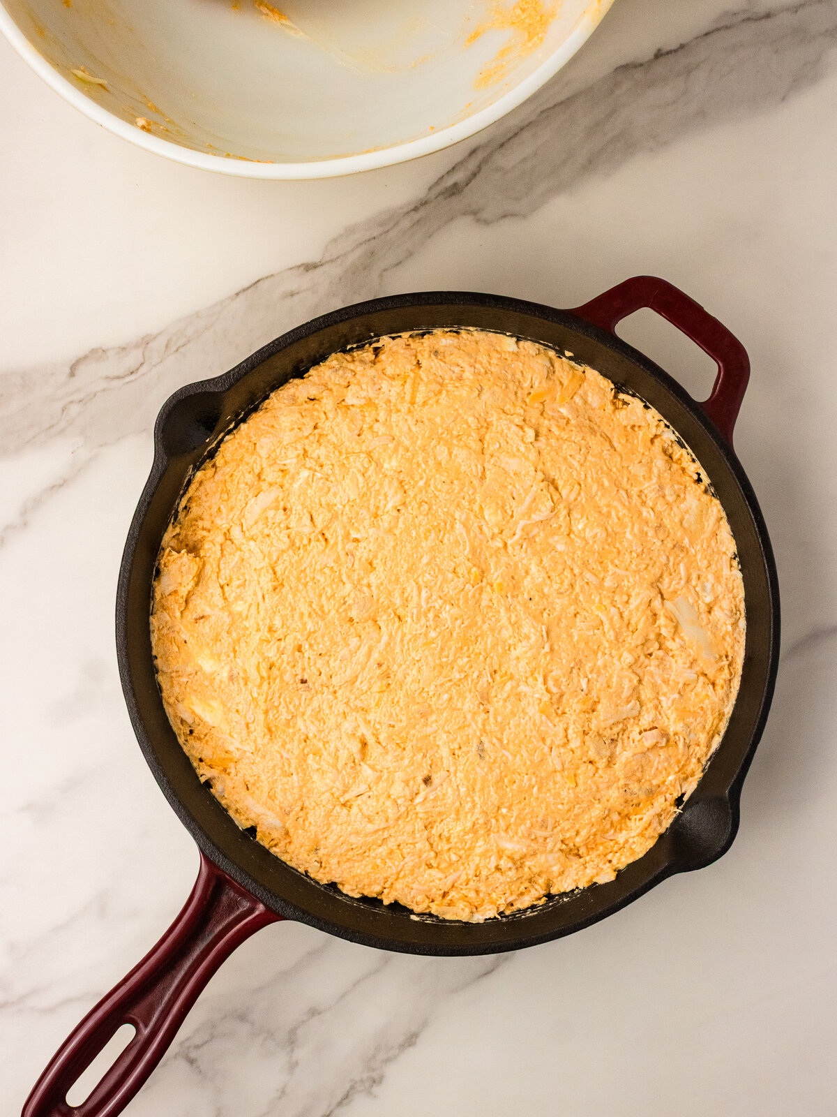Buffalo chicken mixture spread evenly into a cast iron skillet