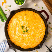 Buffalo chicken dip with rotisserie chicken served in a cast iron skillet with celery carrots and tortilla chips