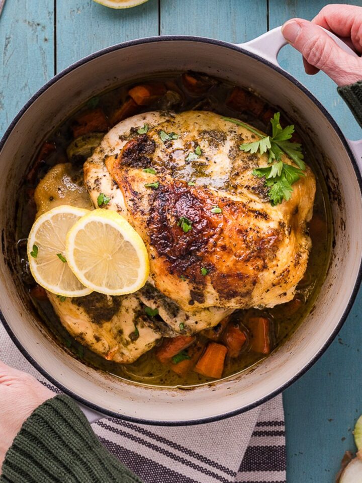 Best Dutch oven for home cooks: an enameled cast iron Dutch oven holding roast chicken and carrots