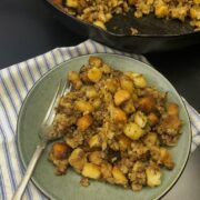A serving of sausage stuffing on a blue plate with a fork, cast iron skillet in the background.