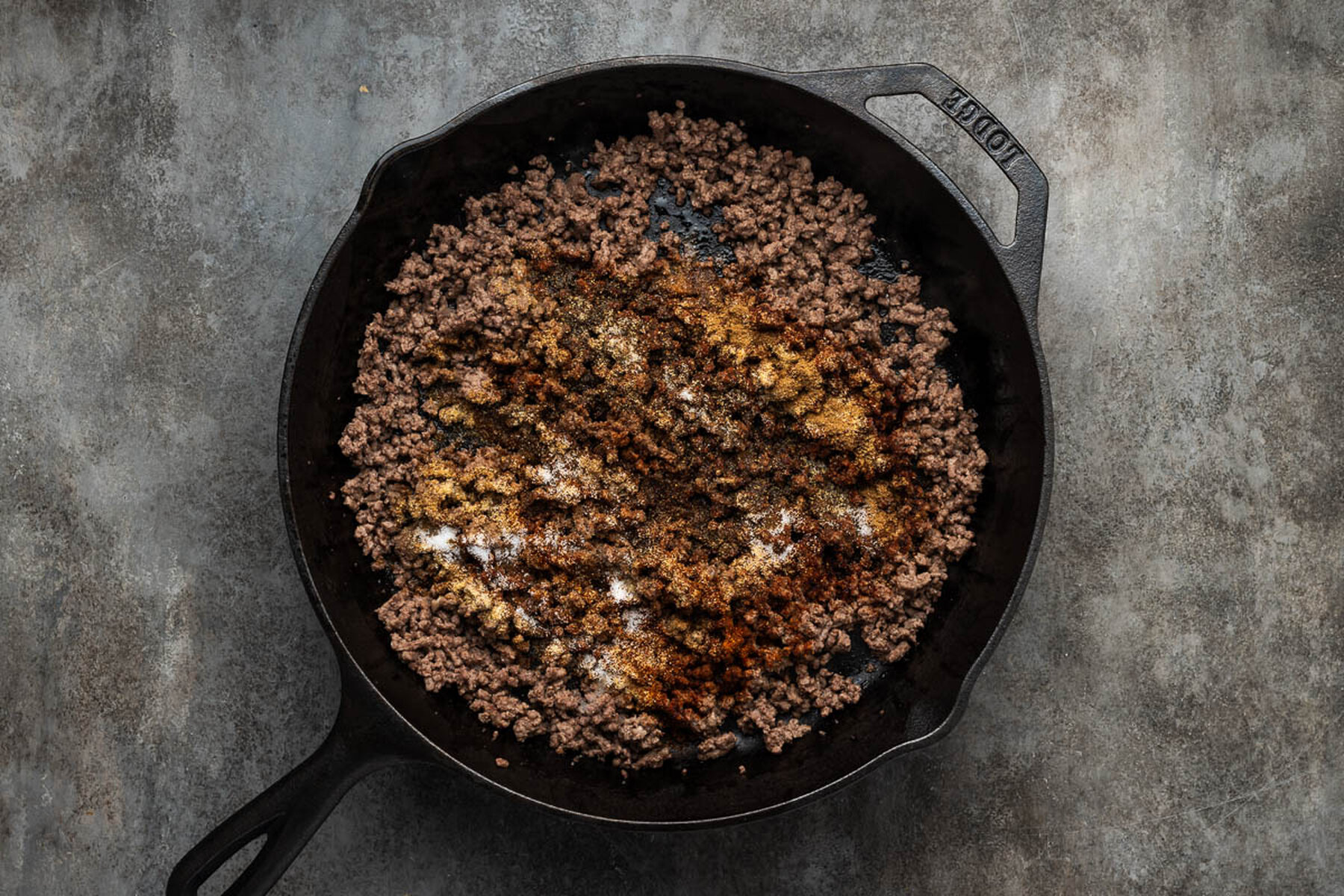 Ground beef broken fine and browning in a 12 inch cast iron skillet