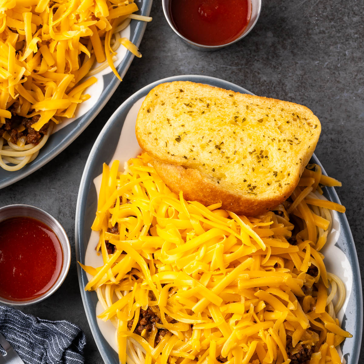 Taco spaghetti served with a thick slice of Texas toast garlic bread and a cup of hot sauce on the side