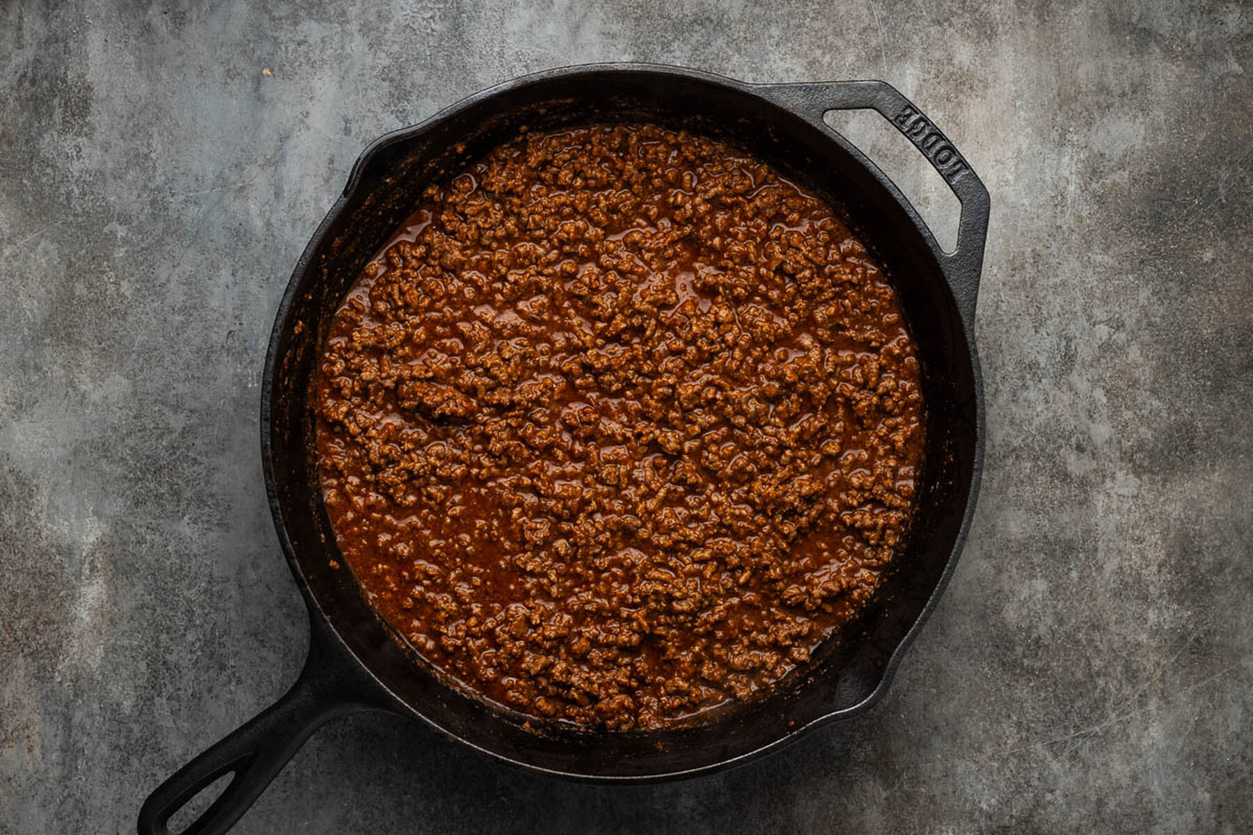 Finished loose taco meat simmered with tomato sauce in a cast iron skillet