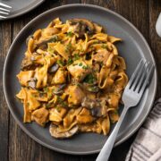 Plate of chicken stroganoff over egg noodles with mushrooms and parsley