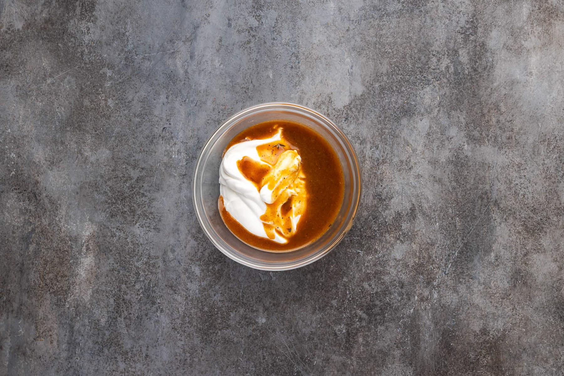 Sour cream whisked with hot sauce in a small glass bowl to temper it