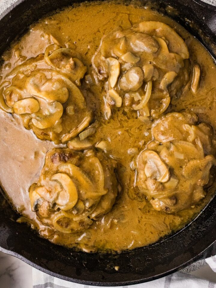 Hamburger steak with mushroom gravy in cast iron skillet square