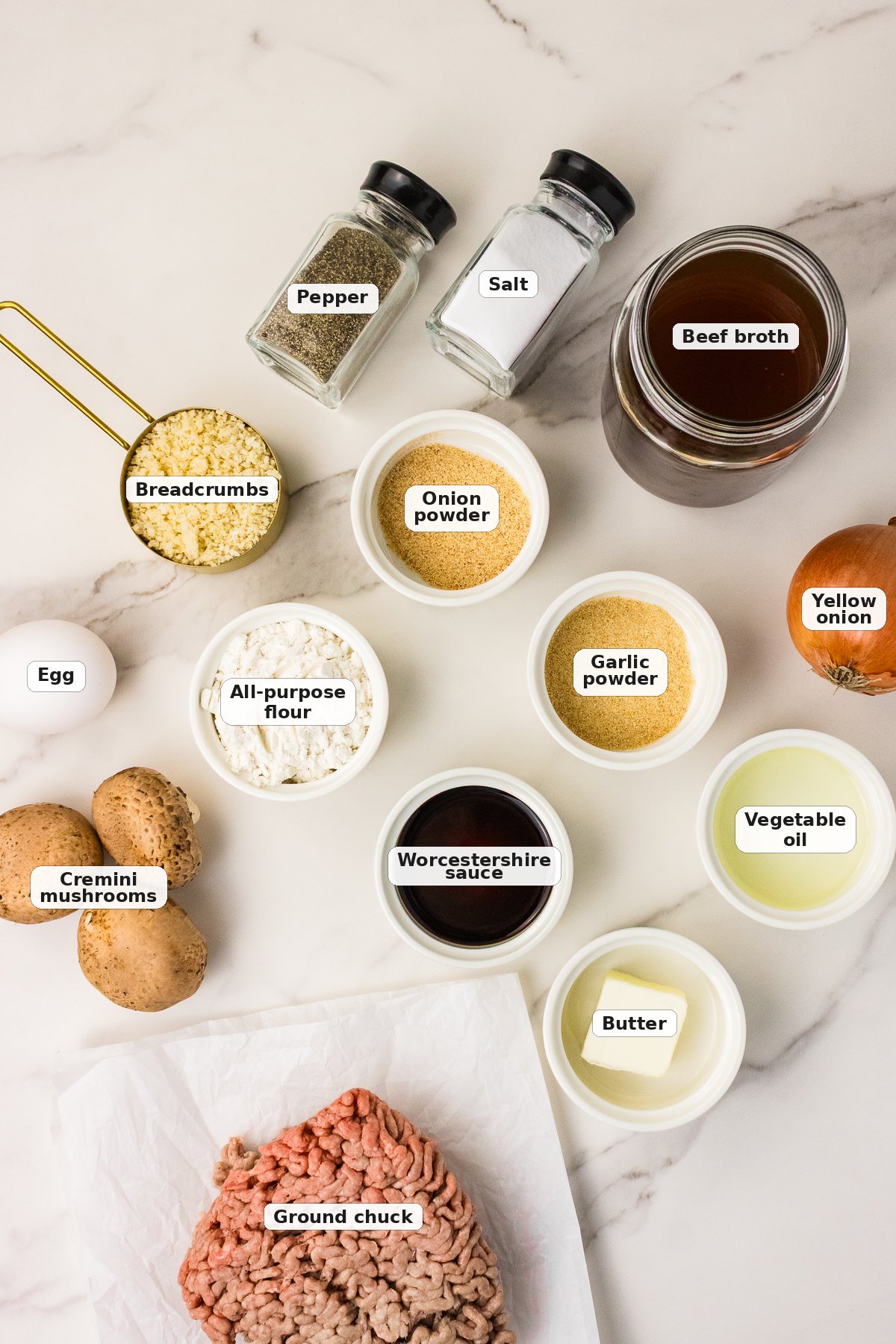 Labeled ingredients for hamburger steak with mushroom gravy: ground chuck, egg, breadcrumbs, garlic powder, onion powder, salt, pepper, vegetable oil, cremini mushrooms, yellow onion, flour, beef broth, Worcestershire sauce, and butter