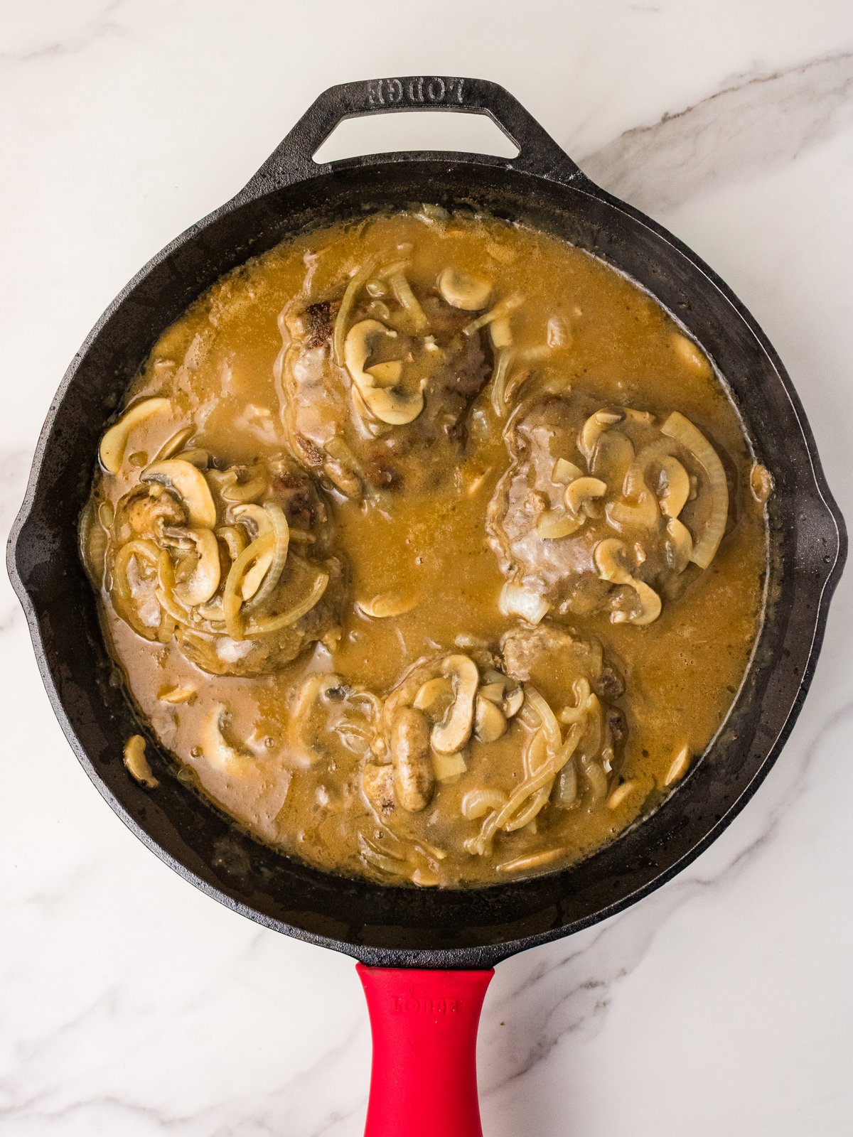 Hamburger steaks simmering in mushroom gravy