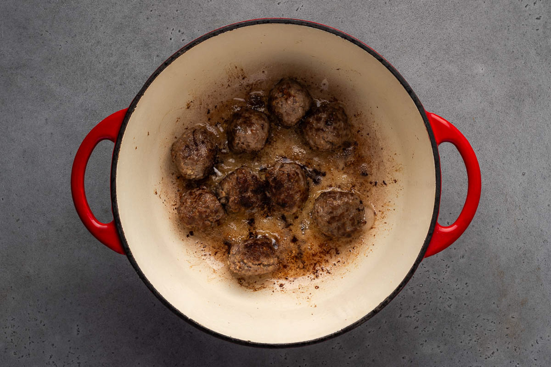 Meatballs browning in an enameled cast iron Dutch oven