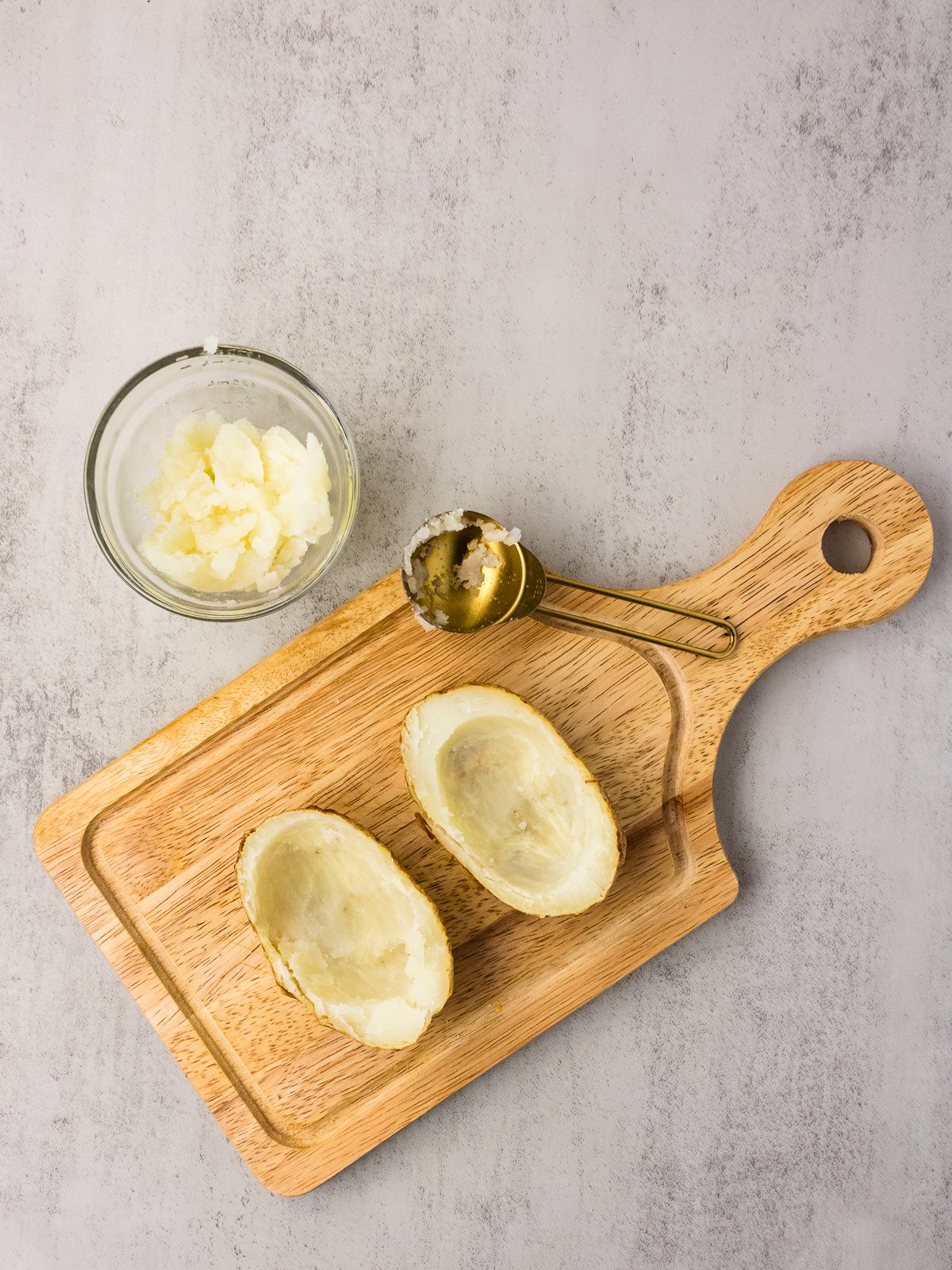 Scooped russet potato shells on a wooden cutting board