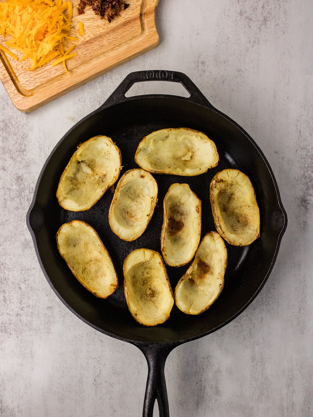 Crisped potato skin shells cut side up in a cast iron skillet
