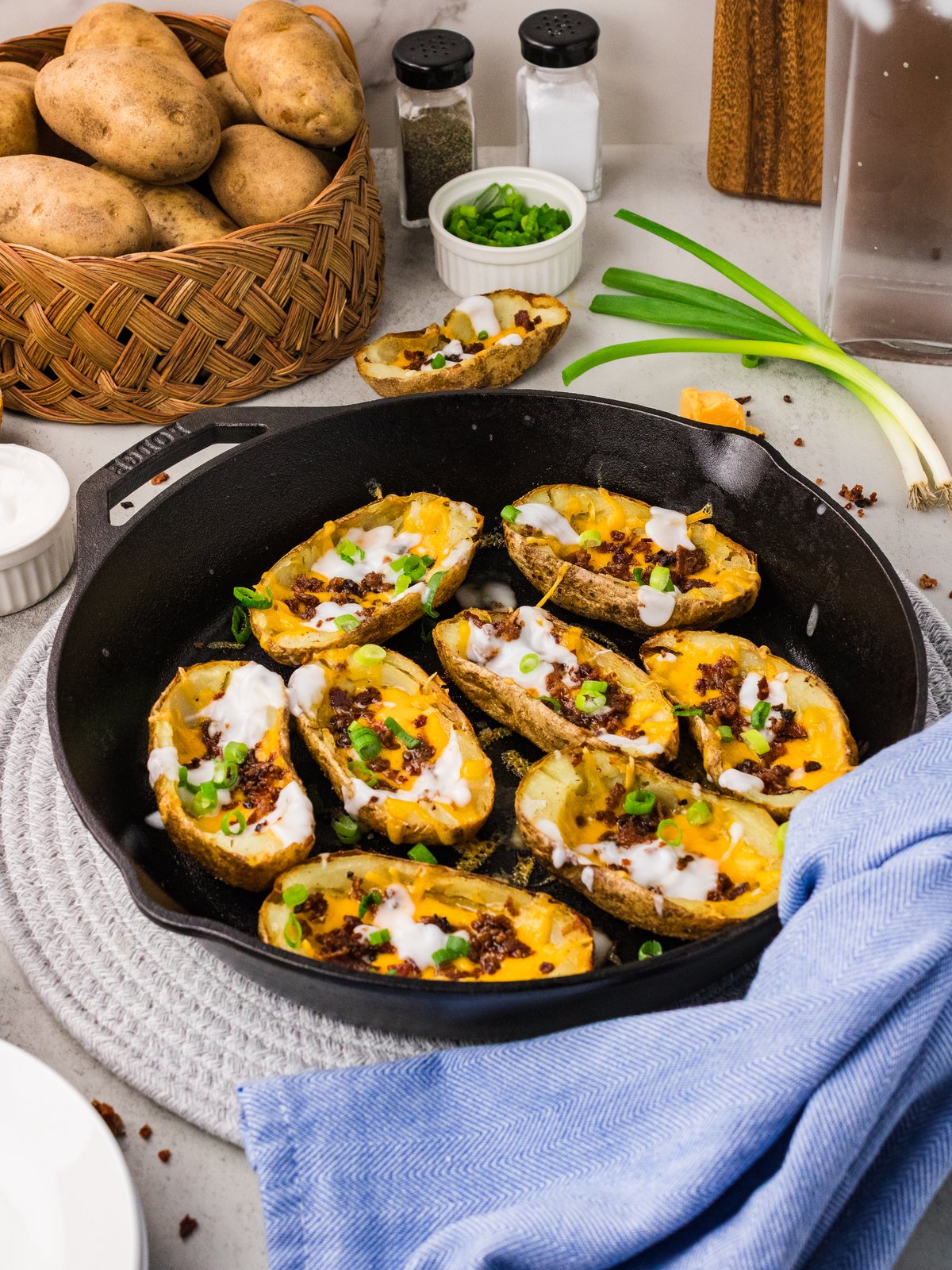 Potato skins loaded with cheddar, bacon, sour cream and green onions in a cast iron skillet