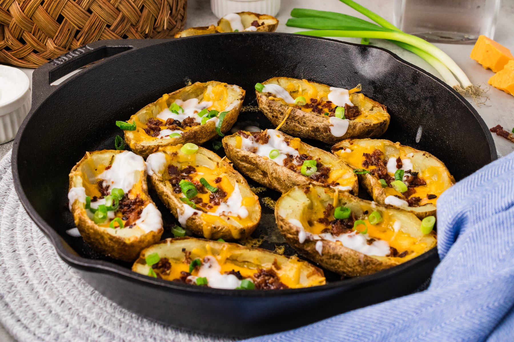 Loaded potato skins in a cast iron skillet with a blue towel